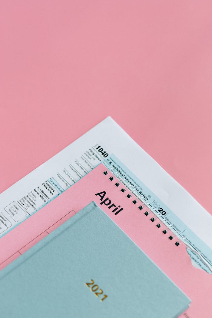 IRS tax form and planner on pastel pink background, symbolizing tax season preparation.